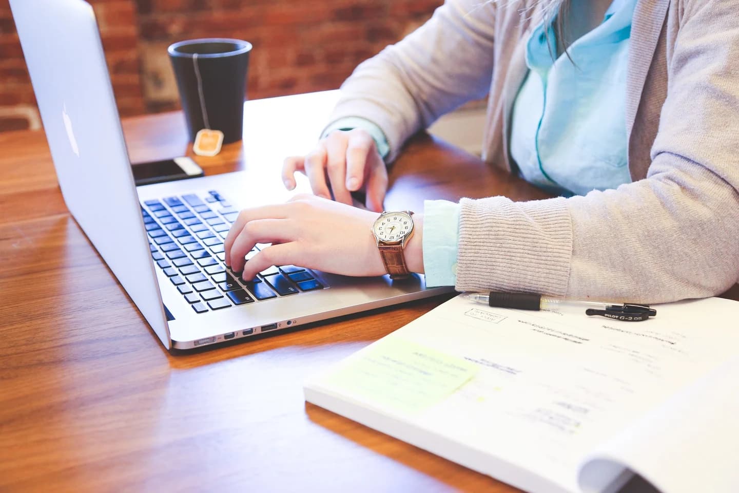 Pessoa estudando com notebook e caderno de anotações sobre a mesa